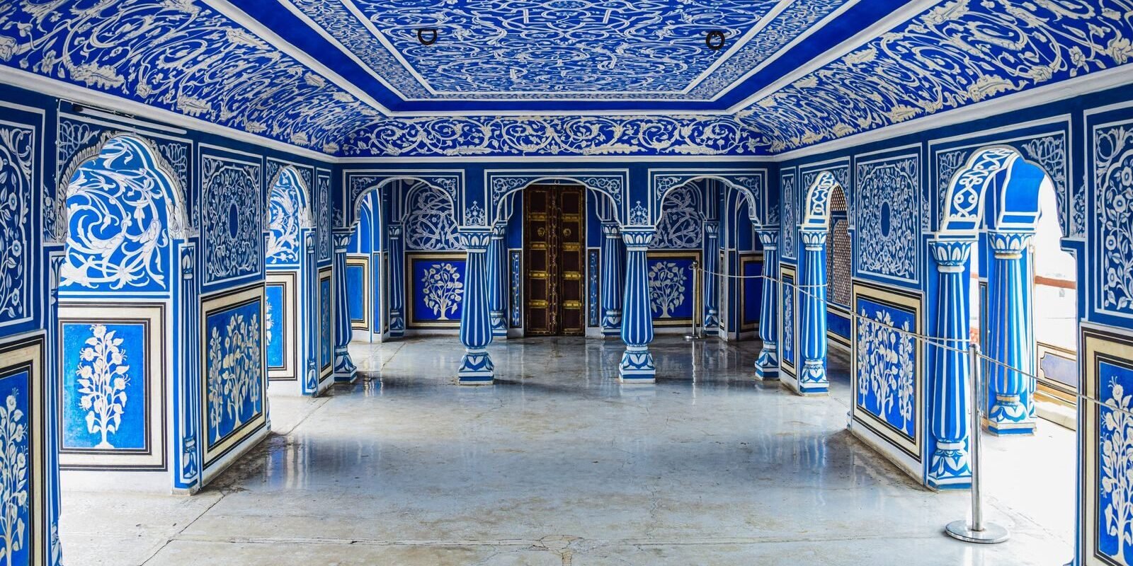 Intricately decorated blue interior of a historic city palace, showcasing vibrant murals and ornate architecture.