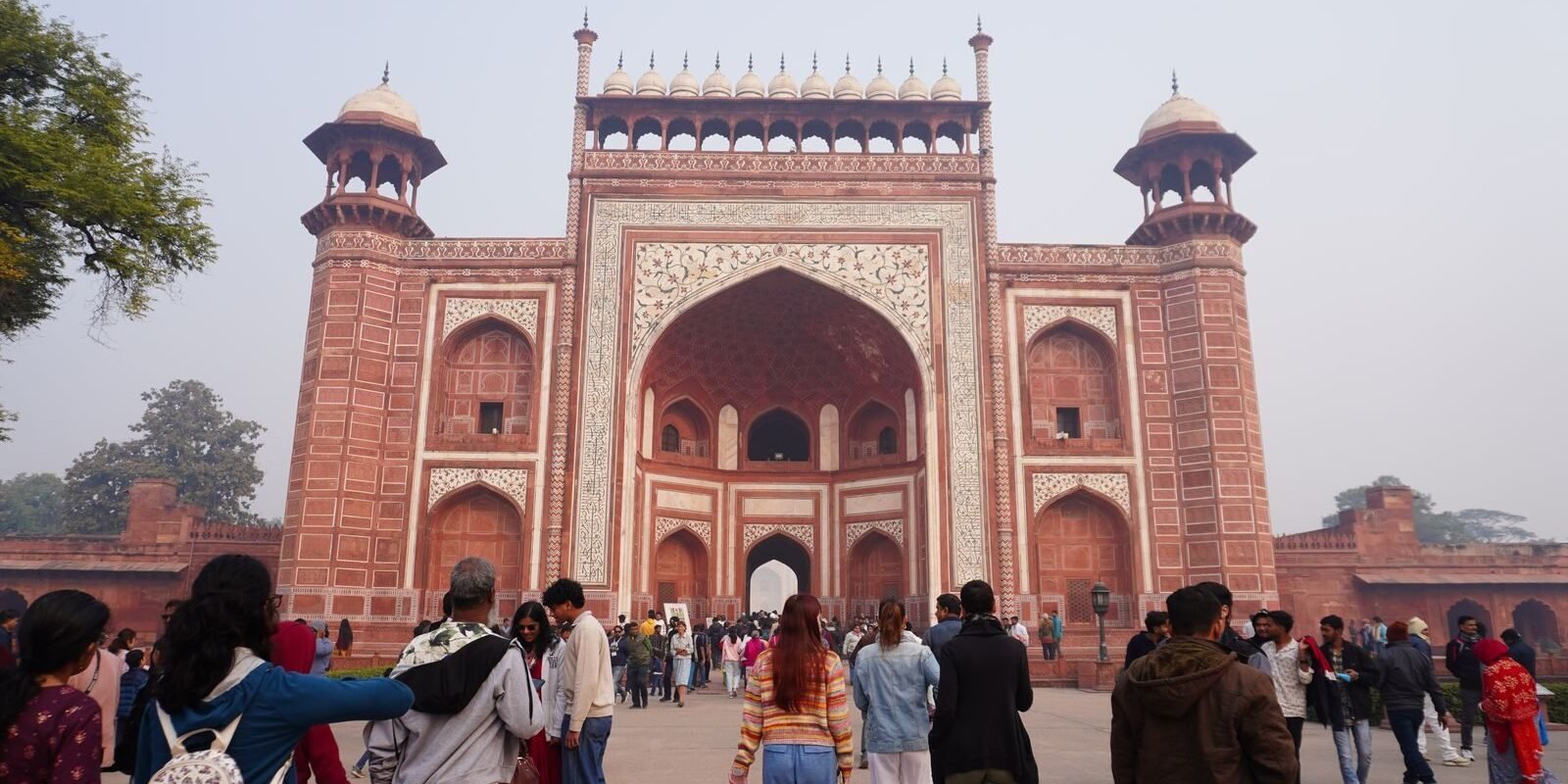 Crowd of visitors at the grand entrance of Agra Fort on a clear day.