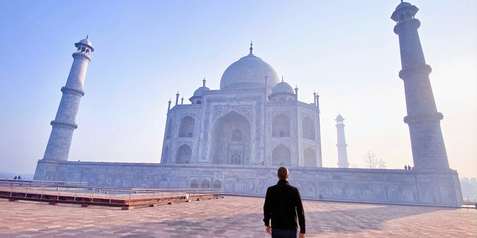 man in black jacket standing near mosque during daytime